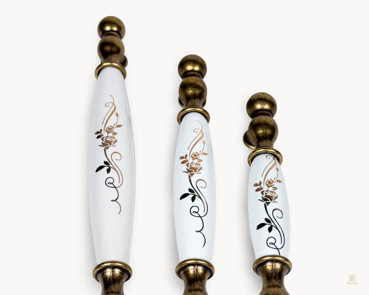 Detailed view of golden scroll motif on white porcelain Belmira handles with antique brass finish