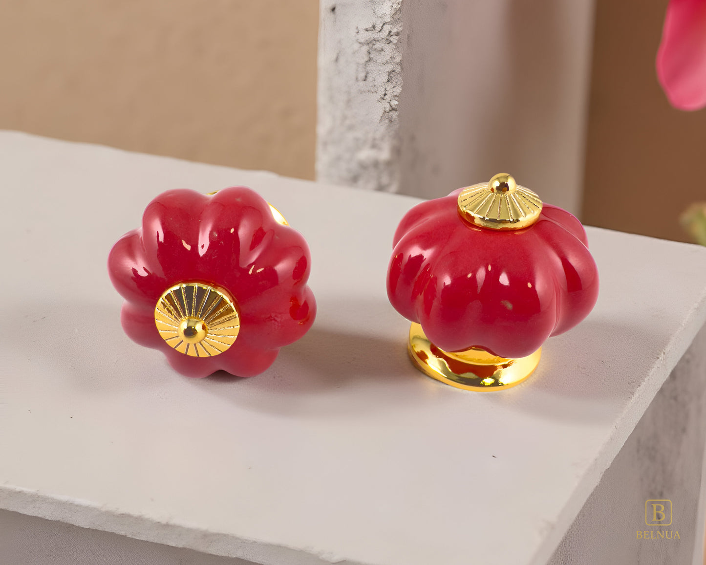 Belnua - Top and front view of delightful Tavira cabinet porcelain knob in red colour with gold metal base in pumpkin shape on marble kitchen worktop