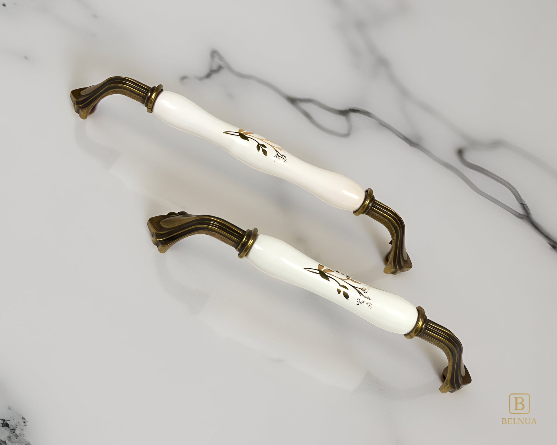 Belnua - ROSMIRA white porcelain/ceramic handle with botanical motif and antique brass finish on marble worktop
