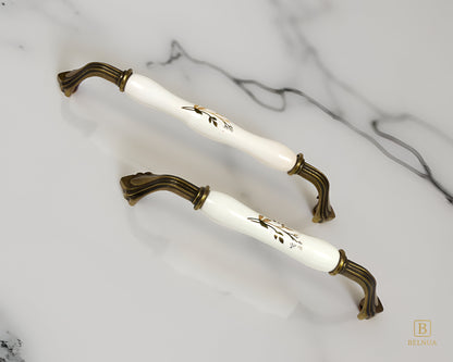 Belnua - ROSMIRA white porcelain/ceramic handle with botanical motif and antique brass finish on marble worktop