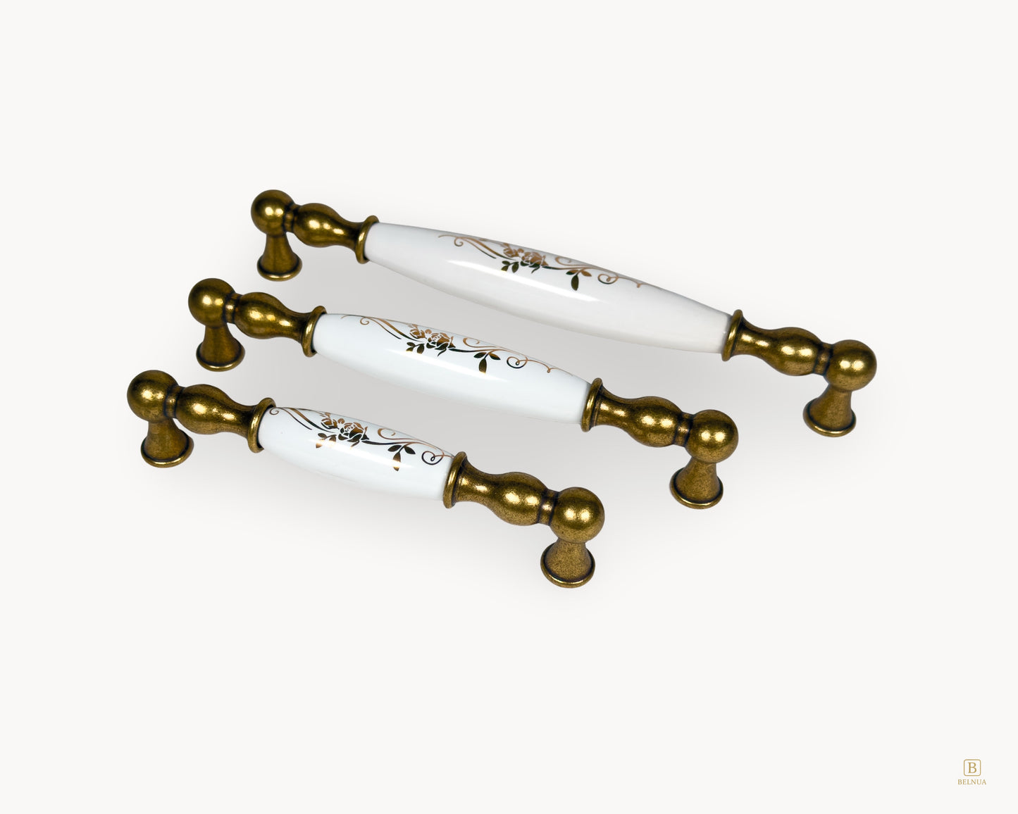 Angled view of Belmira antique brass drawer handles with white porcelain and golden scroll detailing