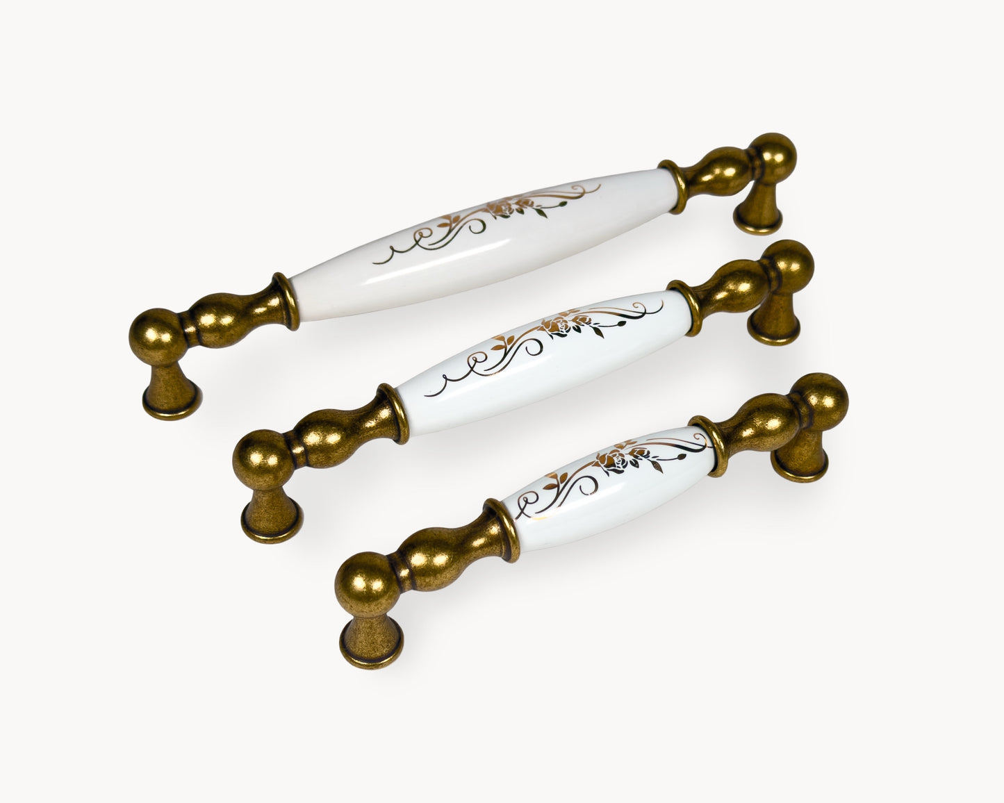 Belmira antique brass cabinet handles with white porcelain inserts and golden scroll motif, shown in 128mm, 160mm and 192mm sizes