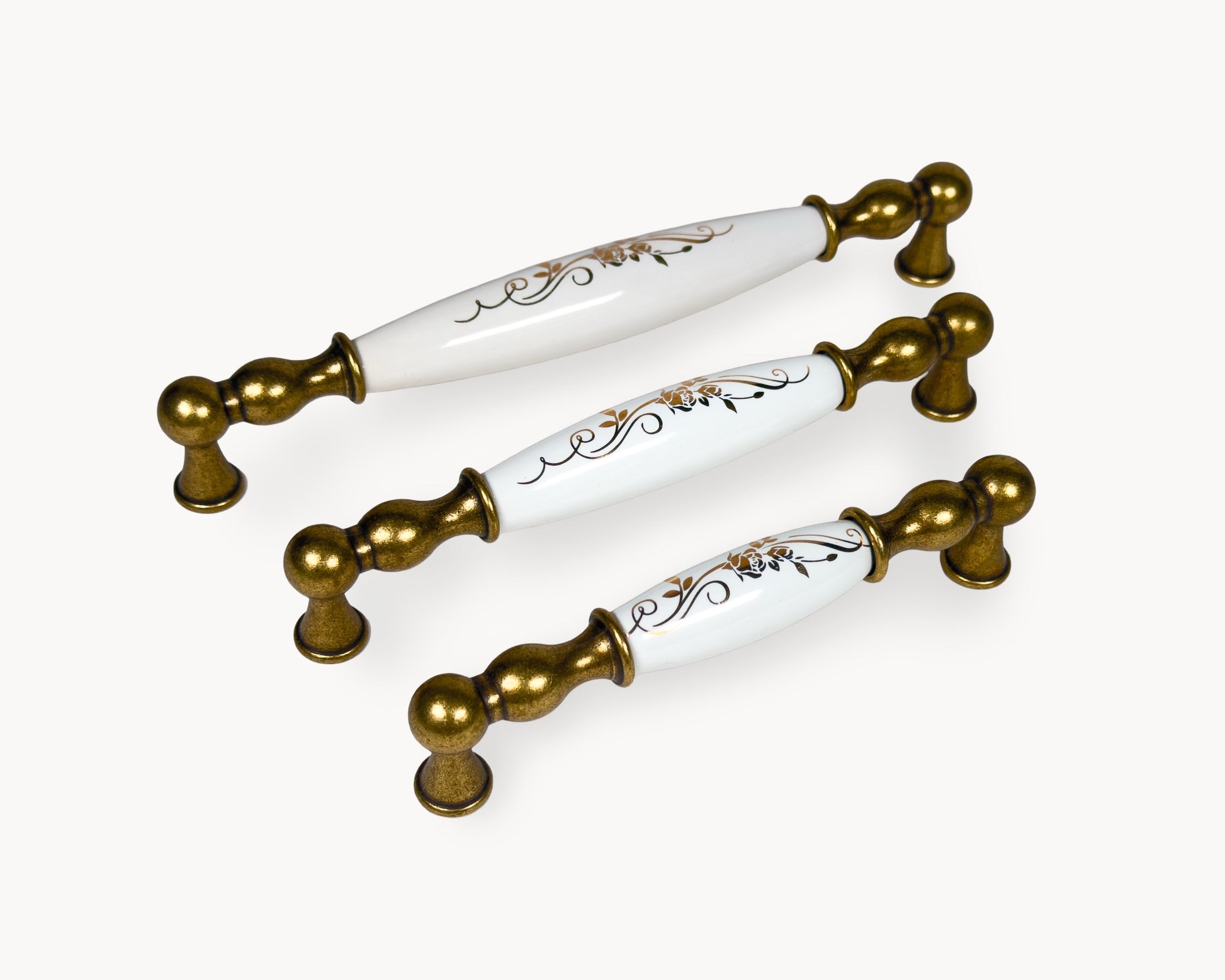Belmira antique brass cabinet handles with white porcelain inserts and golden scroll motif, shown in 128mm, 160mm and 192mm sizes