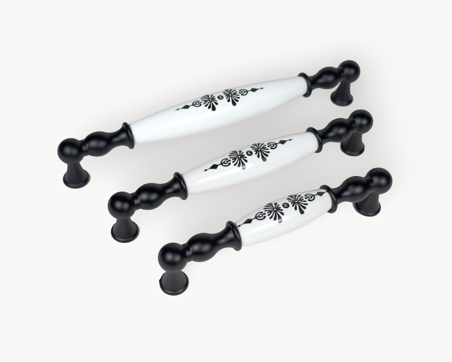 Diagonal arrangement of Belmira black porcelain cabinet handles highlighting the Midnight Blossom decorative detail.