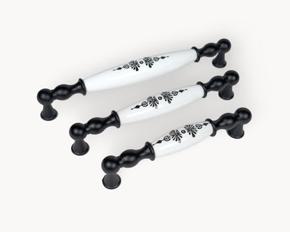 Diagonal arrangement of Belmira black porcelain cabinet handles highlighting the Midnight Blossom decorative detail.
