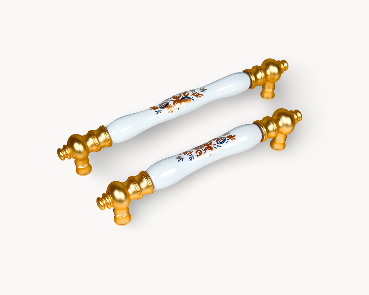 Eloura gold cabinet handles with white porcelain insert and Golden Arch Bloom motif, luxury kitchen hardware shown in angled view