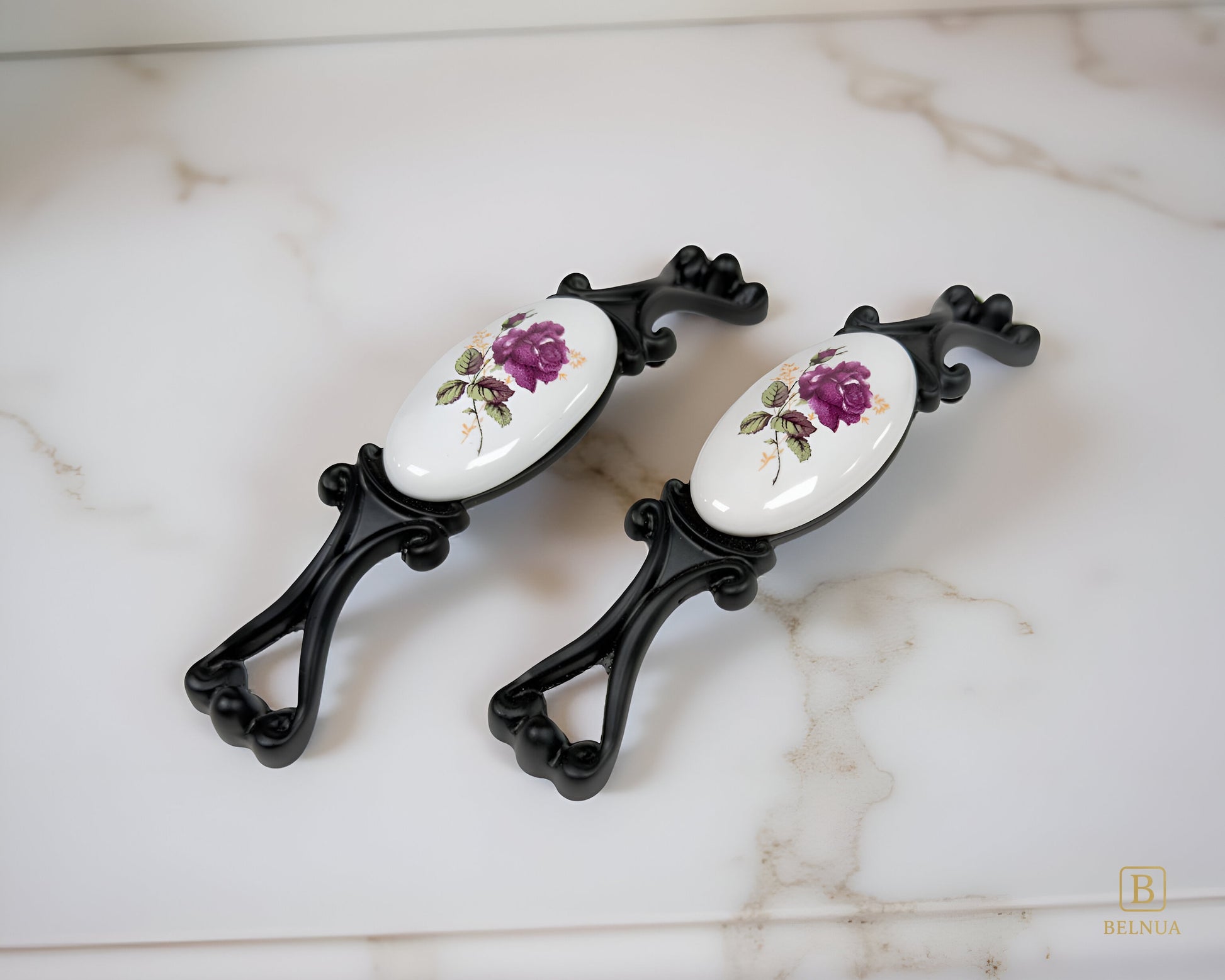 Belnua - Left angled view of Nureya cabinet pull handle with black metal base featuring rose motif on white ceramic/porcelain on marble kitchen worktop