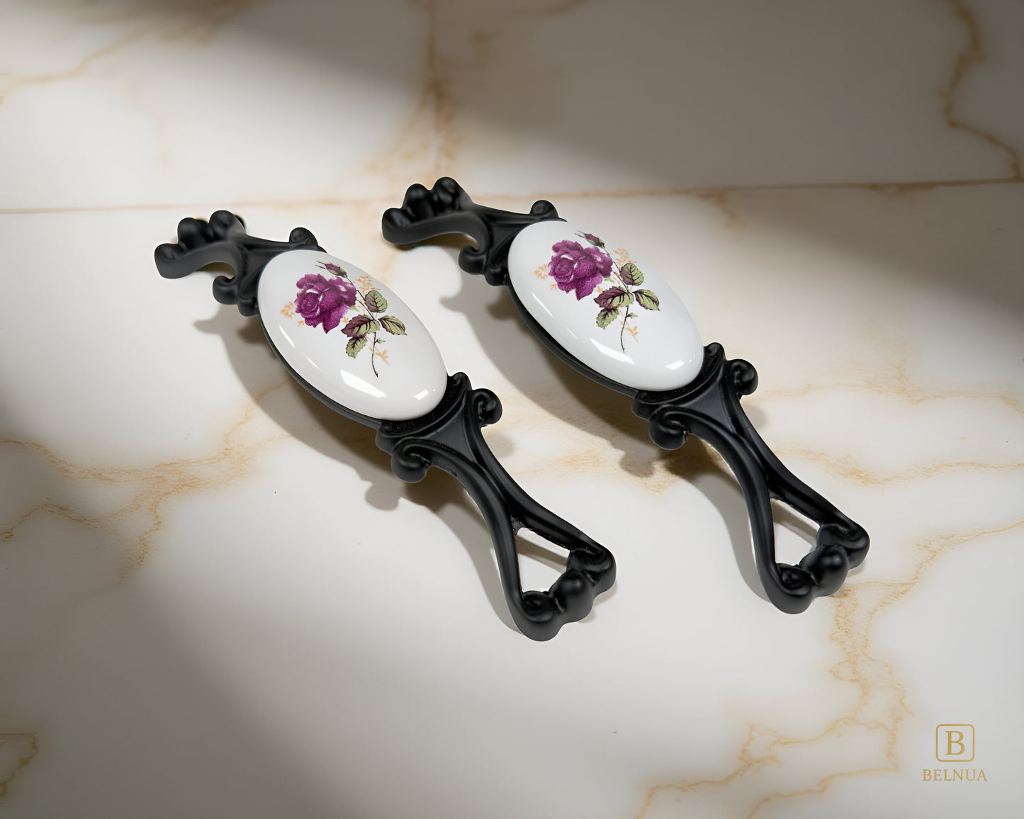 Belnua - Right angled view of Nureya cabinet pull handle with black metal base featuring rose motif on white ceramic/porcelain on crackle marble surface
