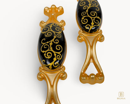 Belnua - Closeup view of Nureya black porcelain pull handle with golden scroll motif