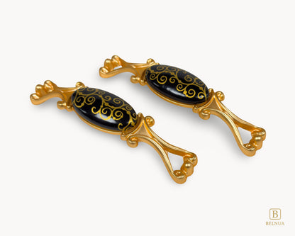 Belnua - Right angled view of Nureya gold cabinet pulls with black ceramic scroll motif