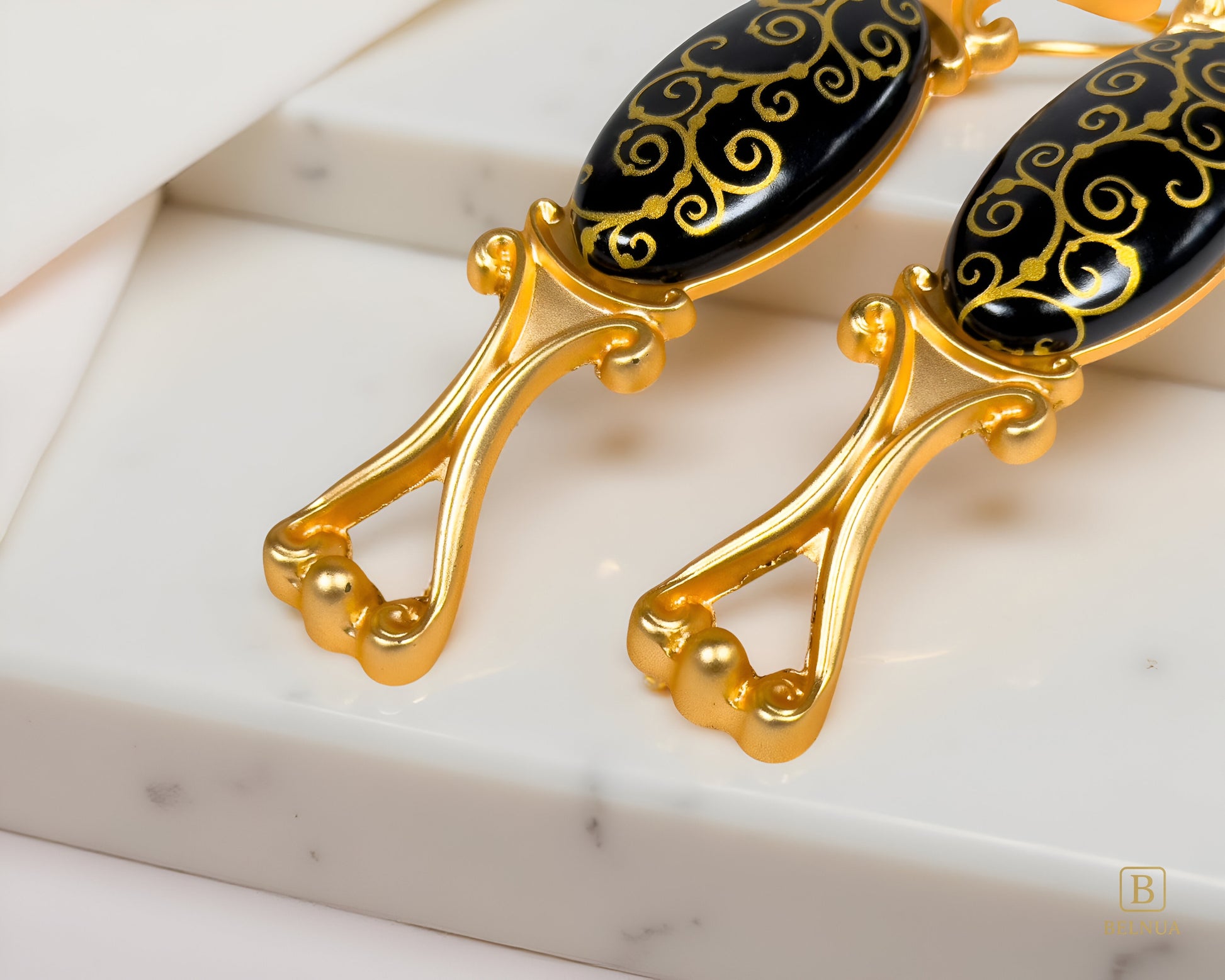Belnua - Pair of Nureya gold cabinet pulls with black ceramic scroll motif with white marble background 