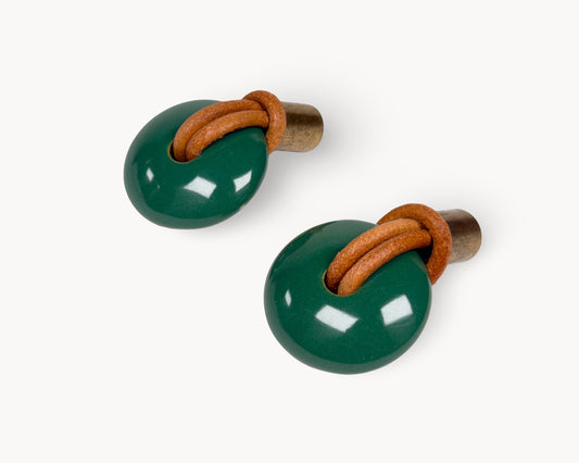A pair of Revina green porcelain drawer knobs with antique brass bases, shown from a perspective angle.