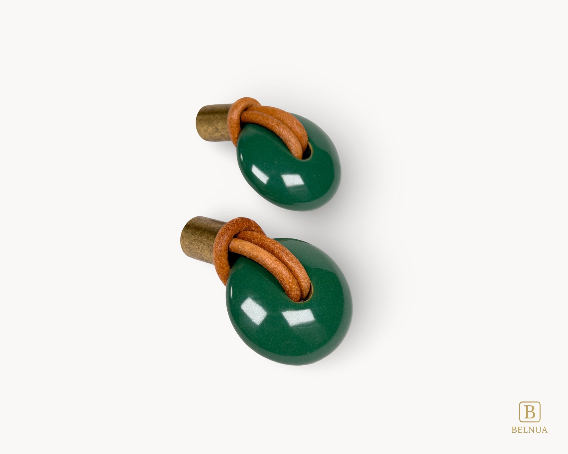 Close-up detail of the genuine leather loop integrated into the green porcelain and antique brass cabinet pull.