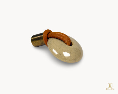 eft-angled view of REVINA porcelain knob highlighting ceramic surface, leather loop and antique brass stem