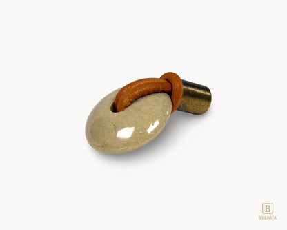 Right-angled view of REVINA porcelain cabinet knob showing curved ceramic body and leather detailing