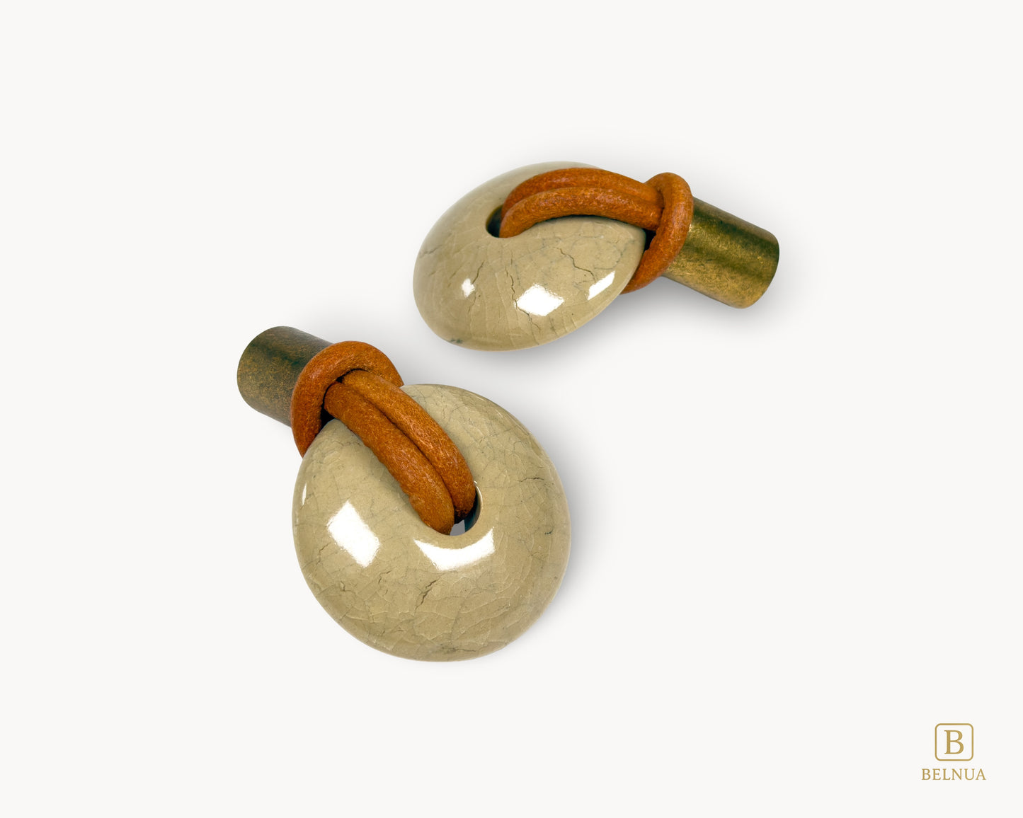REVINA porcelain cabinet knob with antique brass base and brown leather loop, front view on clean white background