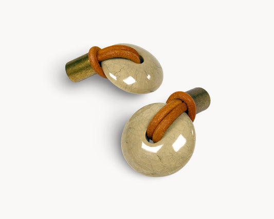 Side view of REVINA porcelain knob showing antique brass stem and leather loop detail