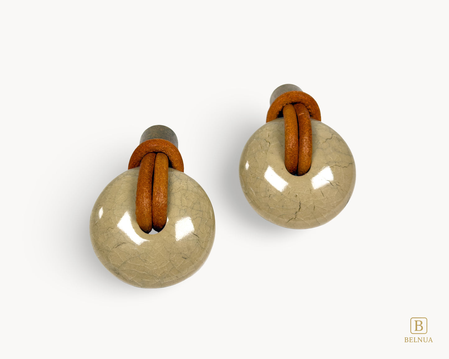 Symmetrical pair of REVINA porcelain knobs with leather loops and antique brass finish