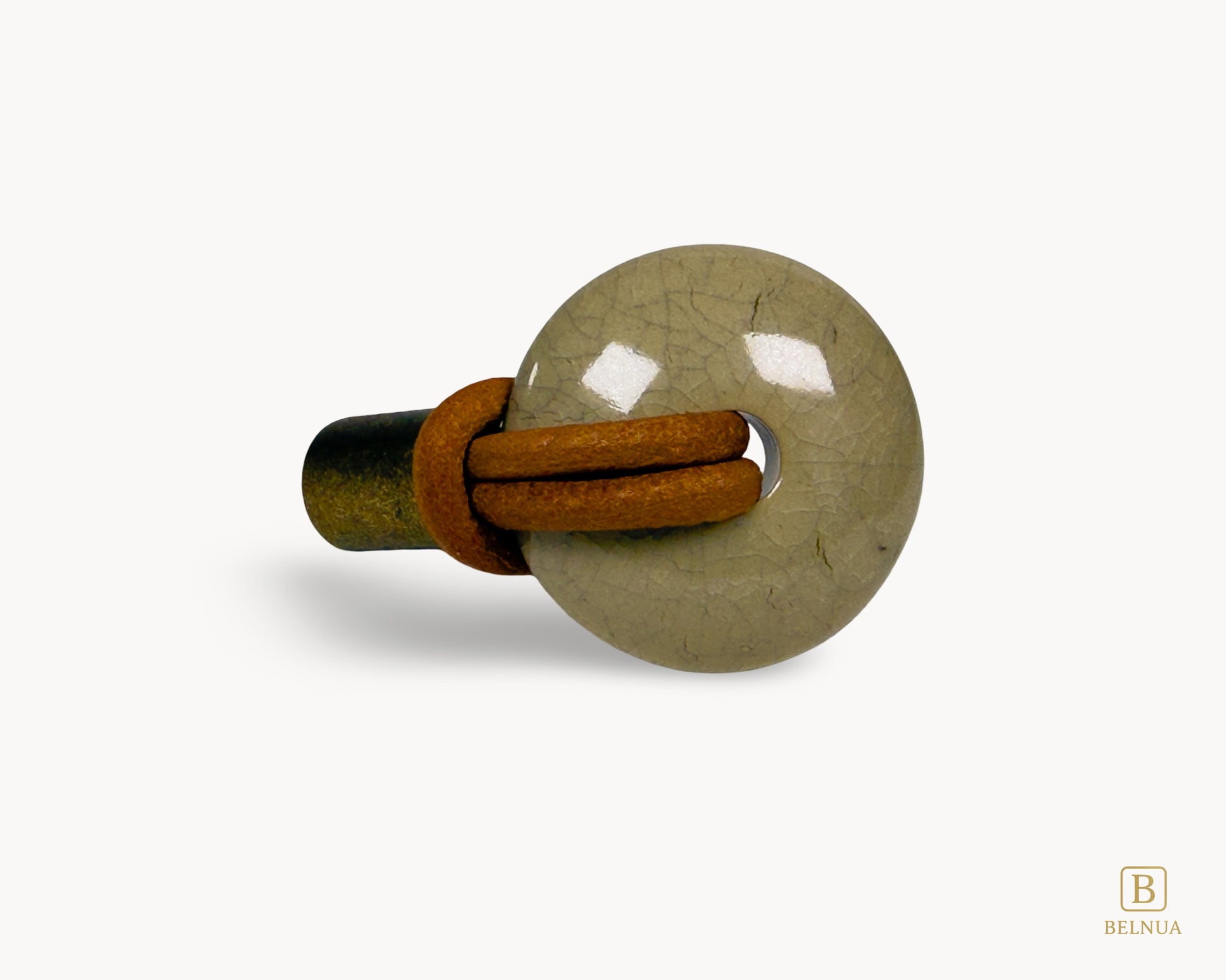 Top-down view of REVINA porcelain knob showing leather loop threading through ceramic with antique brass base