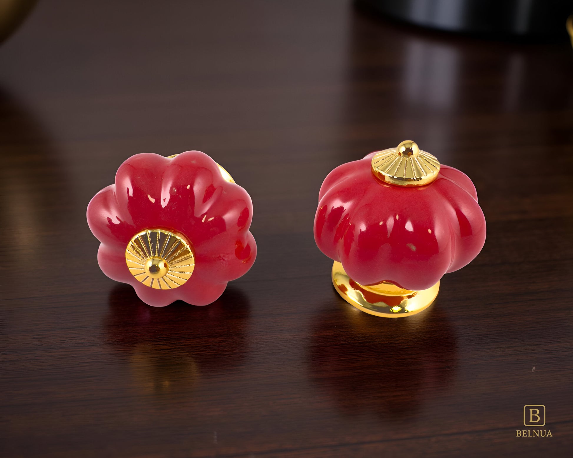 Belnua - Top and front view of Tavira cabinet porcelain knob in red colour with gold metal base on walnut worktop