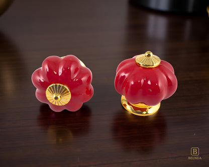 Belnua - Top and front view of Tavira cabinet porcelain knob in red colour with gold metal base on walnut worktop