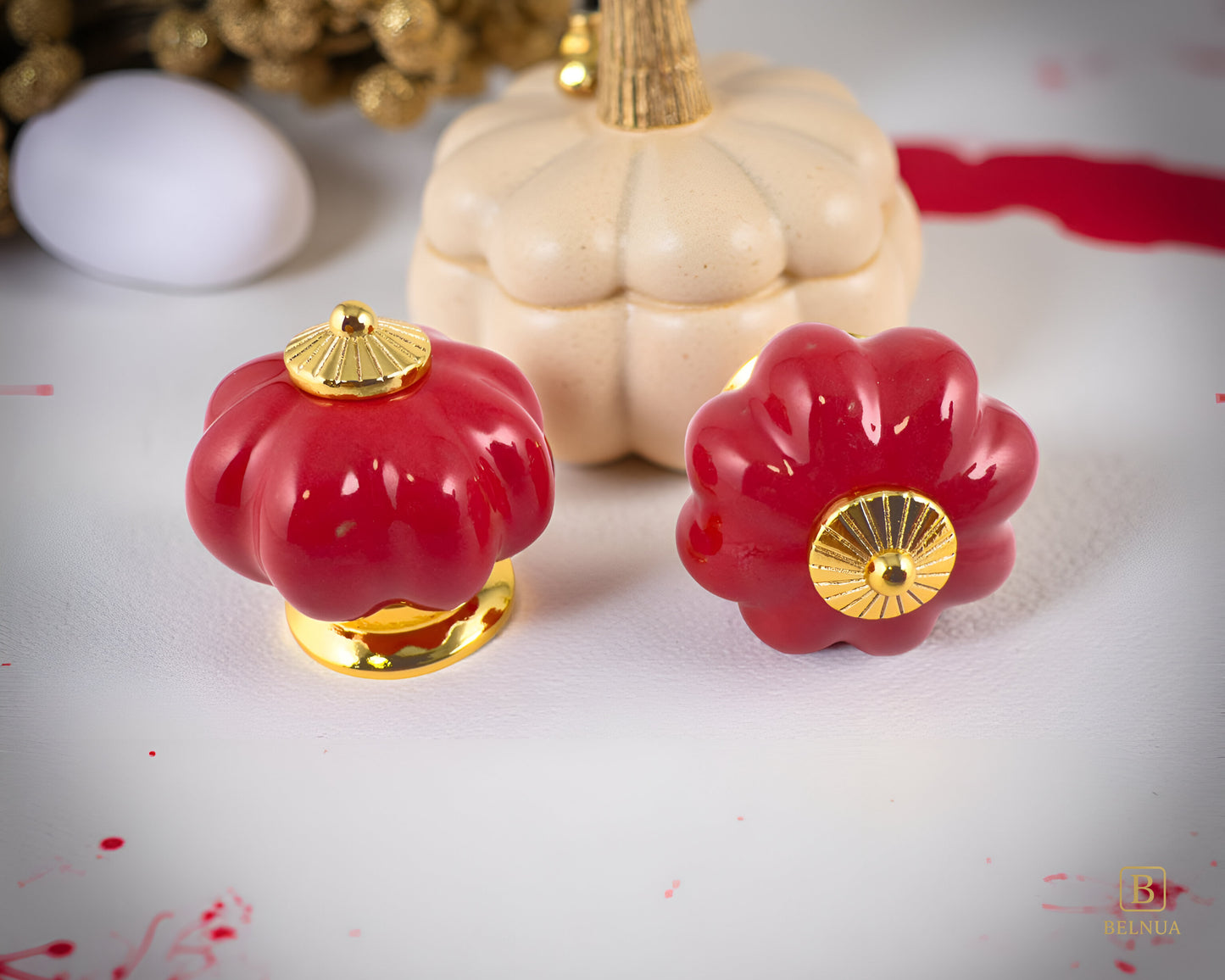 Belnua - Top and front view of Tavira cabinet porcelain knob in red colour with gold metal base in pumpkin shape with pumpkin background