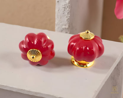 Belnua - Top and front view of delightful Tavira cabinet porcelain knob in red colour with gold metal base in pumpkin shape on marble kitchen worktop