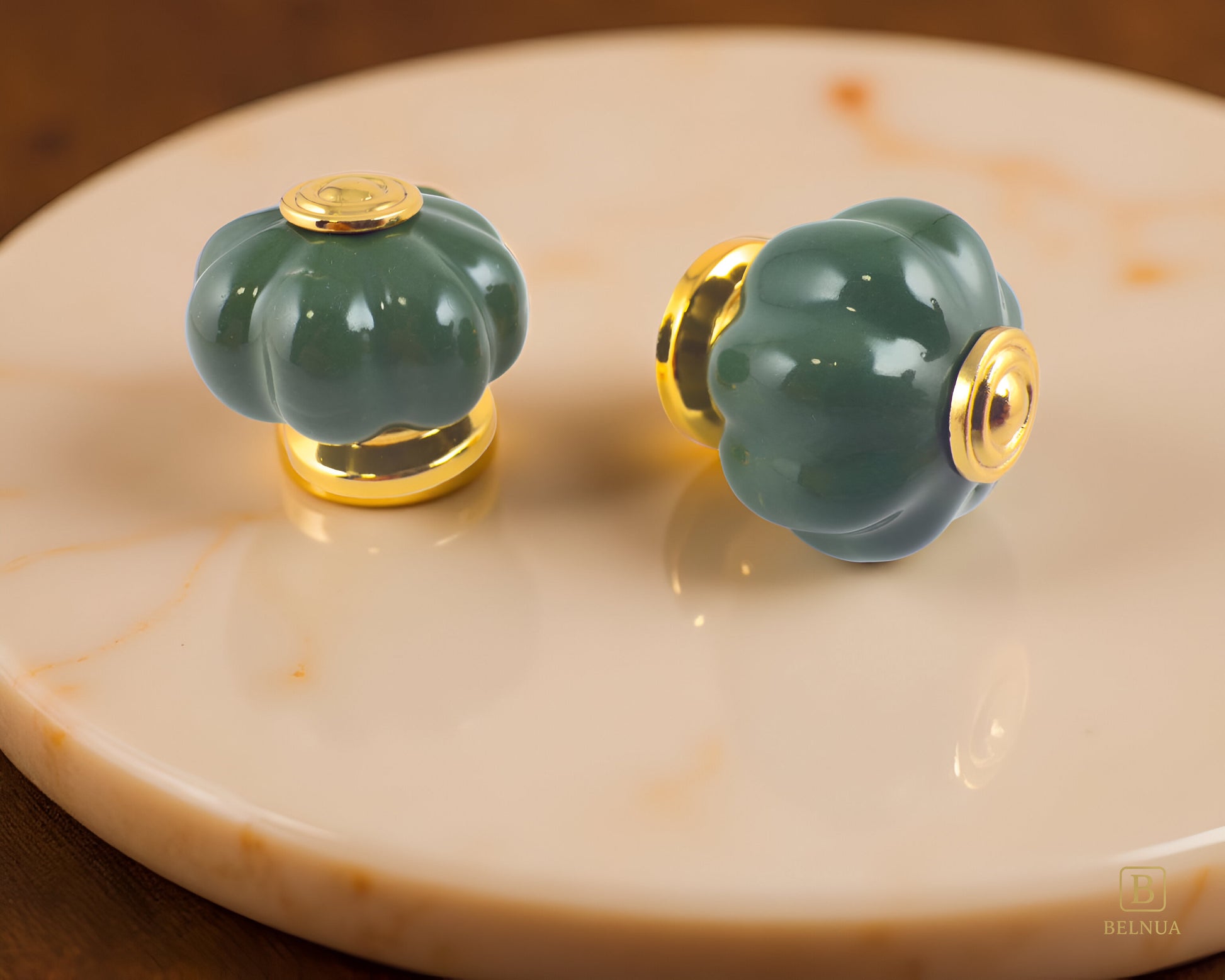 Belnua - Right side and top view of Tavira gold base knob pair with dark green porcelain insert  on orange marble surface