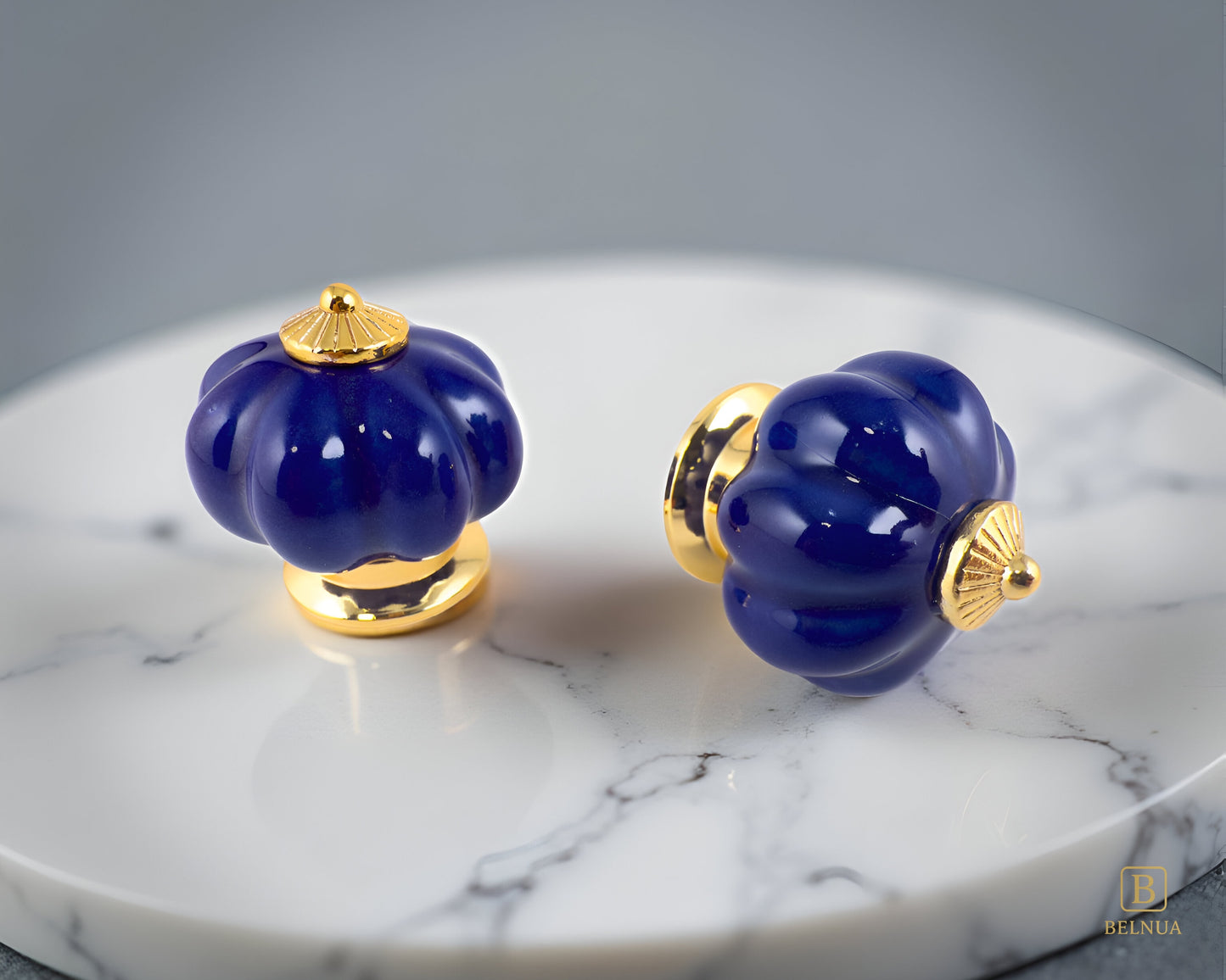 Belnua - Top and right side view of Tavira porcelain cabinet knob with cobalt colour in pumpkin design with gold metal base on marble plate