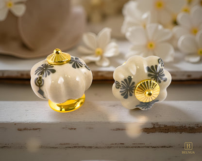 Belnua -Top and front view of Tavira antique brown cabinet porcelain/ceramic knob with gold base featuring golden regal wreath motif on floral background and vintage wood background