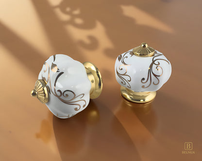 Belnua - Top and left side view of Tavira porcelain cabinet knob with gold metal base on kitchen marble worktop present delicate gold pedal motif