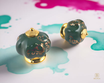 Belnua - Top and right side view of luxury Tavira green porcelain cabinet knob pair with delicate golden vine cascade motif inserted gold metal base featuring on green and pink pastoral background
