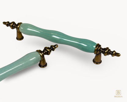 Belnua - Close up view of VELNOA cabinet handle pair in antique brass finish with turquoise porcelain insert showing brass and ceramic details