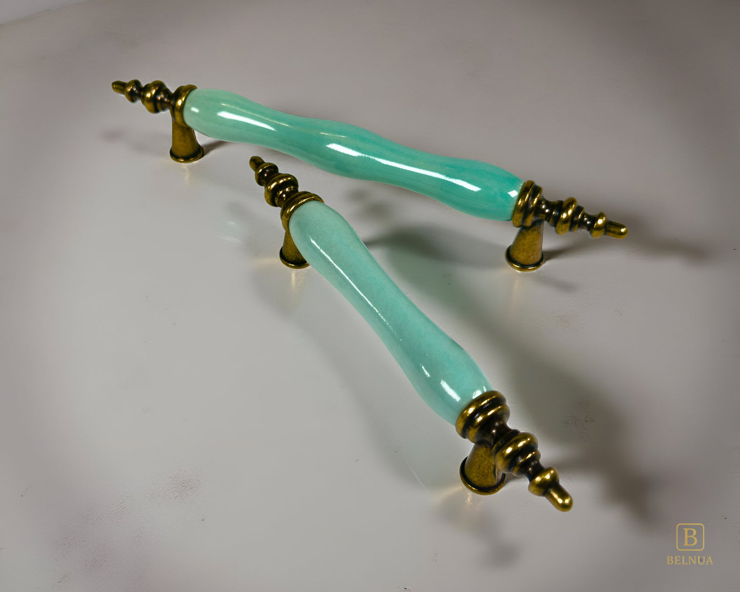 Belnua - Pair of VELNOA cabinet handle in antique brass finish with turquoise porcelain insert with light grey background  showing brass details
