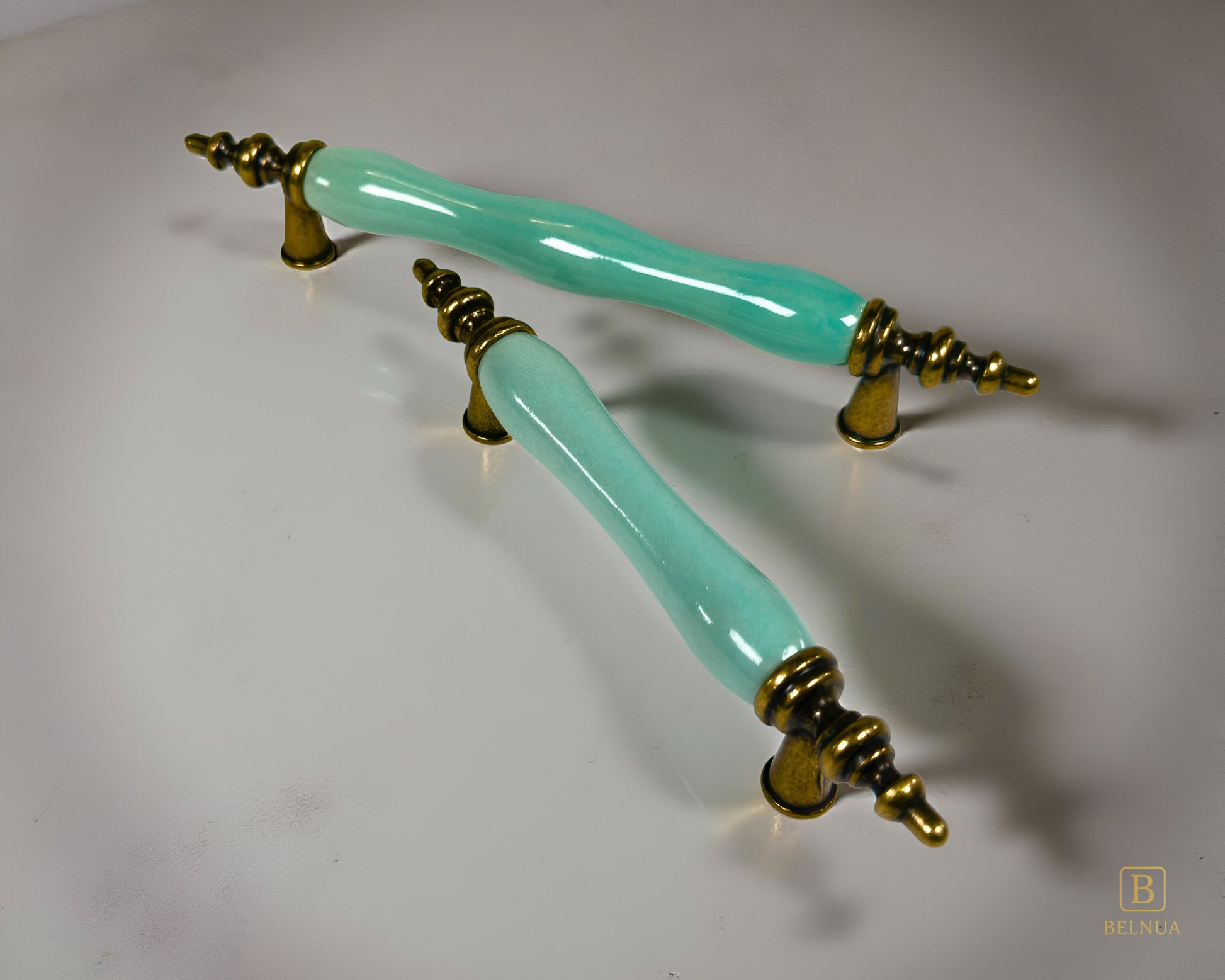 Belnua - Pair of VELNOA cabinet handle in antique brass finish with turquoise porcelain insert with light grey background  showing brass details