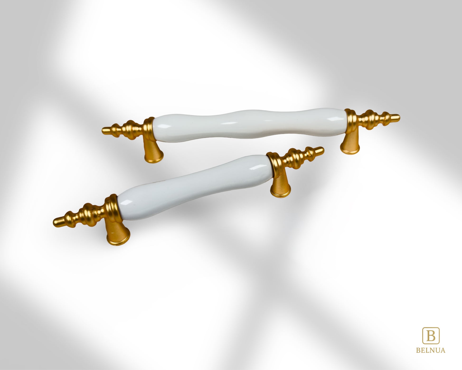 Belnua - Top angled view of Velnoa matte gold cabinet handle pair with plain white porcelain/ceramic insert with shadows