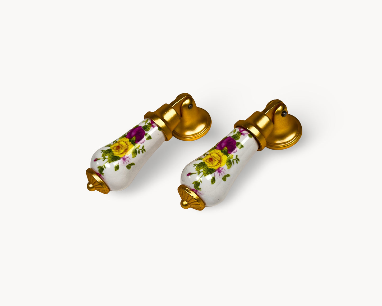 Pair of Verossa porcelain cabinet handles with floral pattern and matte gold base on white background.
