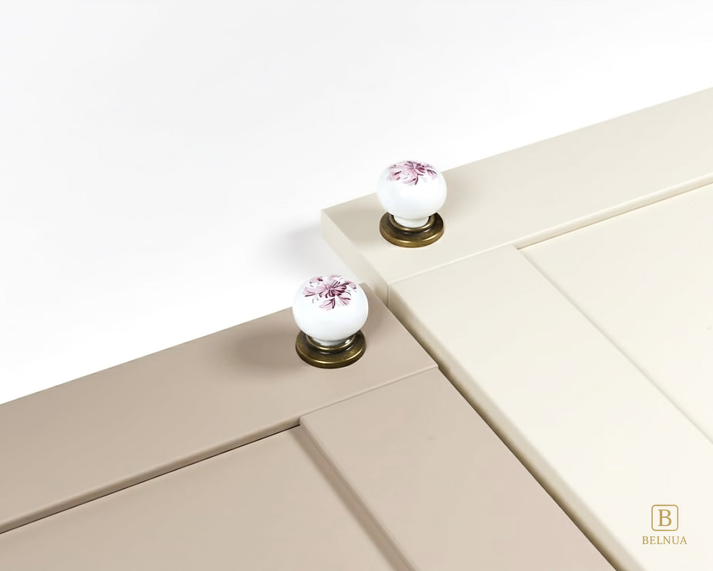 Belnua - Close up top view of ZERRA white porcelain/ceramic knob pair with antique brass base featuring with cashmere and light taupe cabinet door
