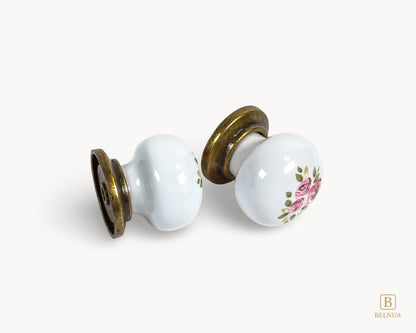Belnua - Flat lay view of ZERRA porcelain/ceramic white knob pair in vintage style antique brass finish with Wildflower Garden design