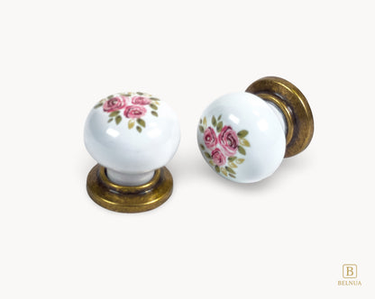 Belnua - Flat lay top and front view of delicate ZERRA porcelain/ceramic white knob pair in vintage style antique brass finish with Wildflower Garden design