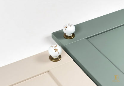 Close-up of cream and sage green kitchen cabinet with Zerra white knobs  | Belnua