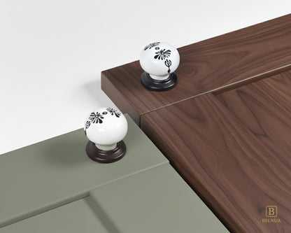 Belnua - ZERRA black and white porcelain knob with midnight blossom motif on sage green and walnut cabinet door