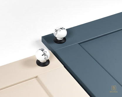 Belnua - ZERRA porcelain/ceramic white knob with botanical motif on black base showcasing with cream & navy blue cabinet door