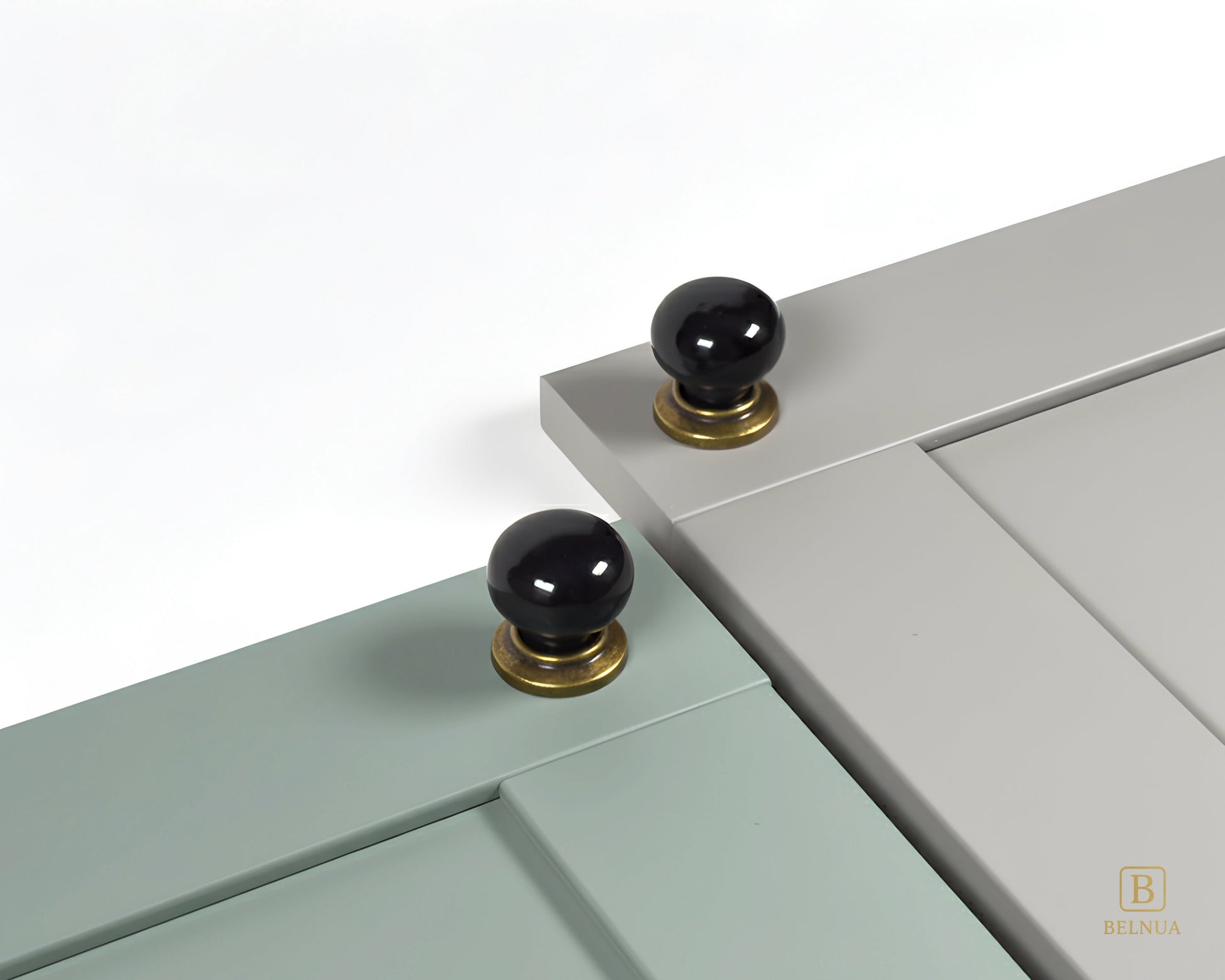 Close-up of a sage green and stone grey cabinet door with black knobs and brass bases from Zerra collection | Belnua