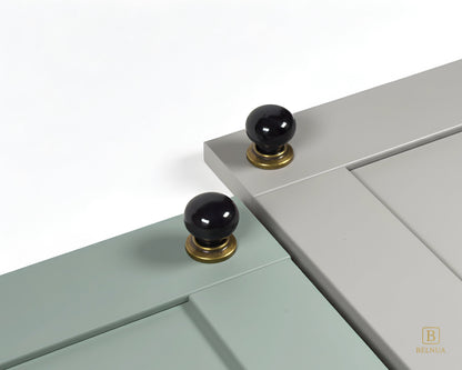 Close-up of a sage green and stone grey cabinet door with black knobs and brass bases from Zerra collection | Belnua