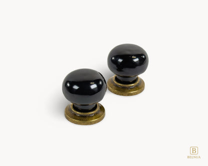 Pair of top view of black porcelain knobs and brass bases from Zerra collection | Belnua