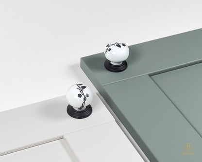Belnua - Styled cream and sage green cabinet door featuring ZERRA black leaf porcelain knob