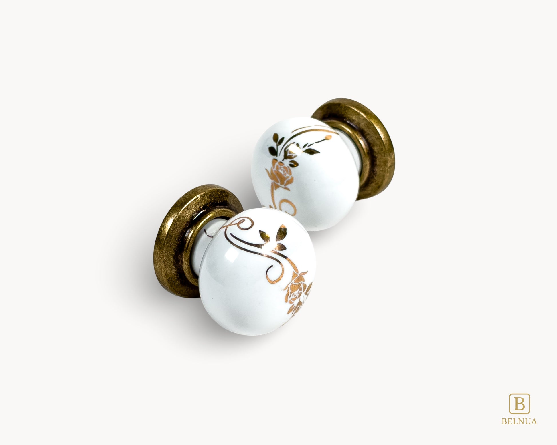 Belnua - Flat lay view of ZERRA white ceramic/porcelain knob with golden scroll motif and antique brass base