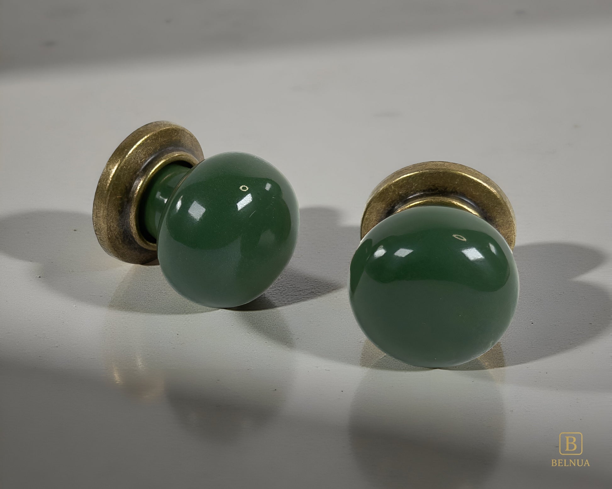 Belnua - Pair of flat lay of antique brass knob with dark green porcelain insert with grey background