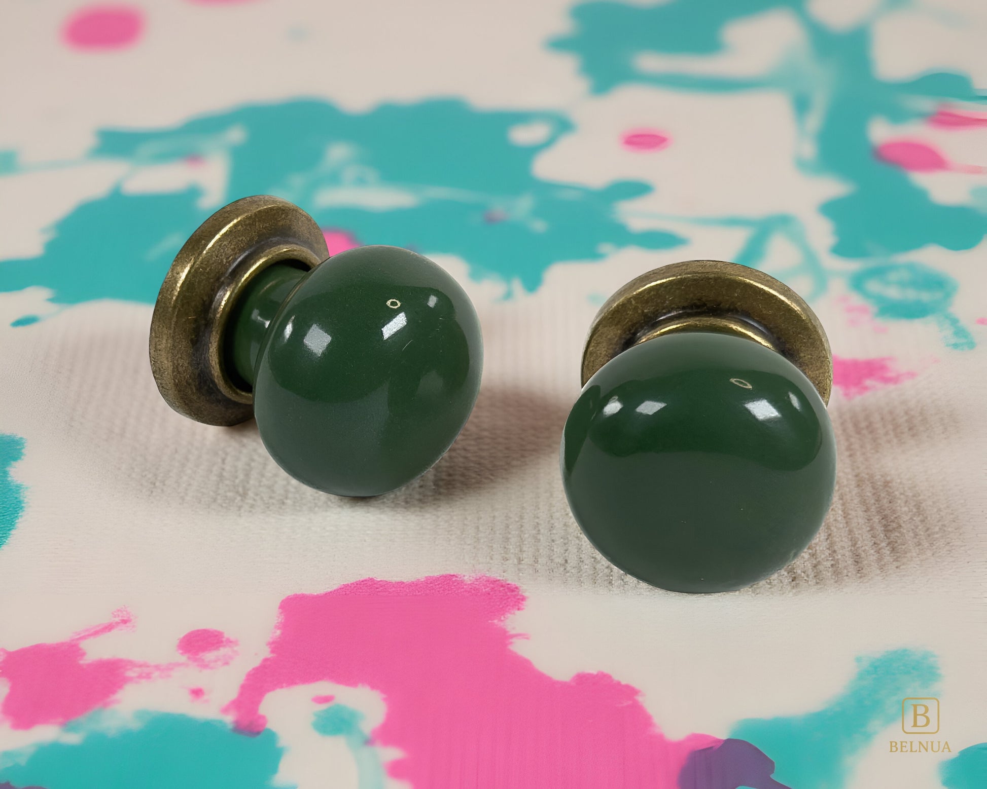 Belnua - Pair of flat lay of antique brass knob with dark green porcelain insert with colourful splash background